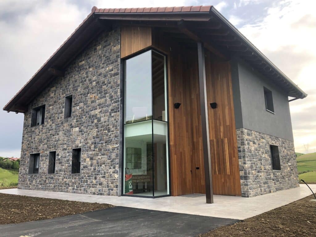 Fachada de piedra y madera con ventanales